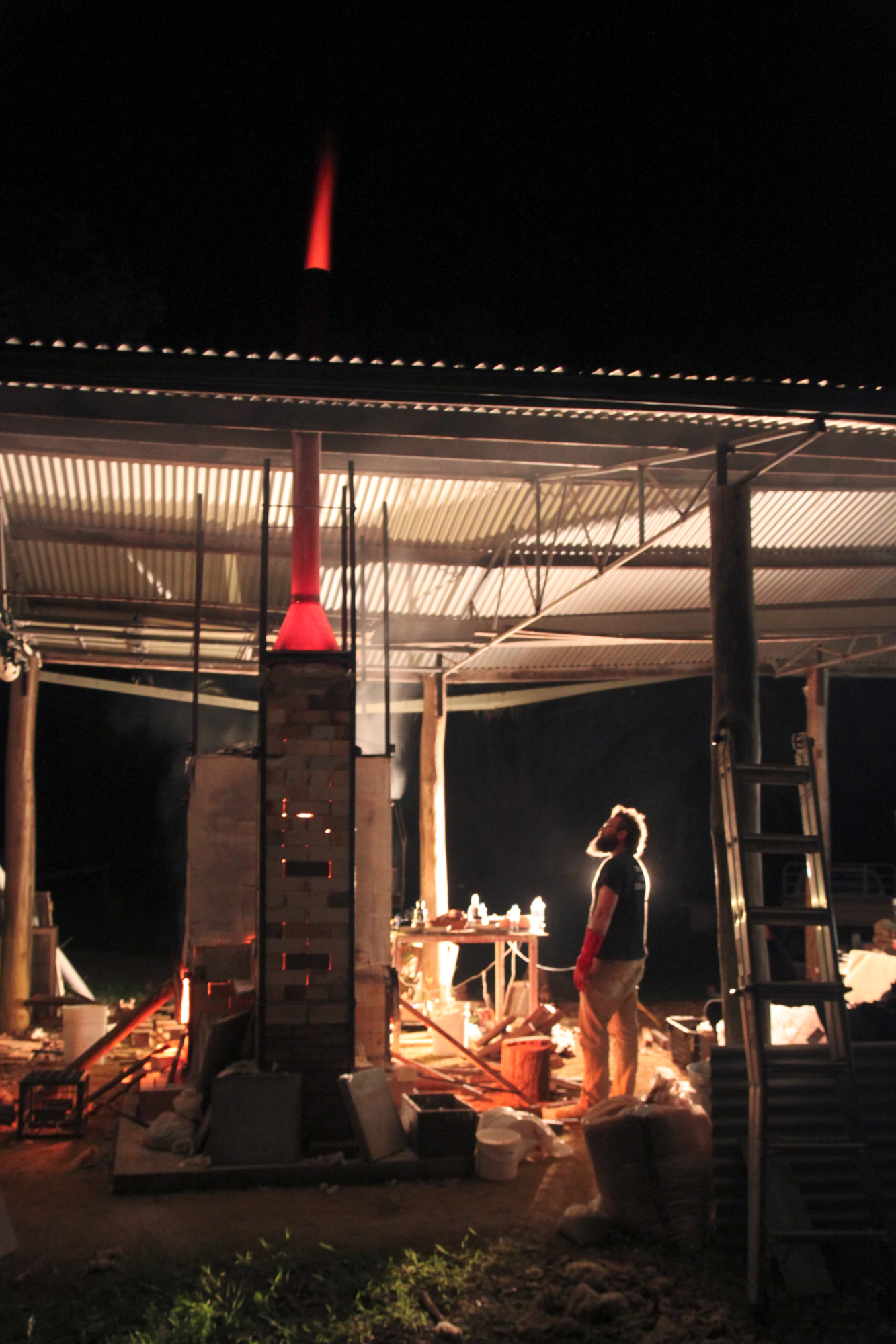 Image: Harry looks up at red flame emerging from the chimney of the wood fired kiln